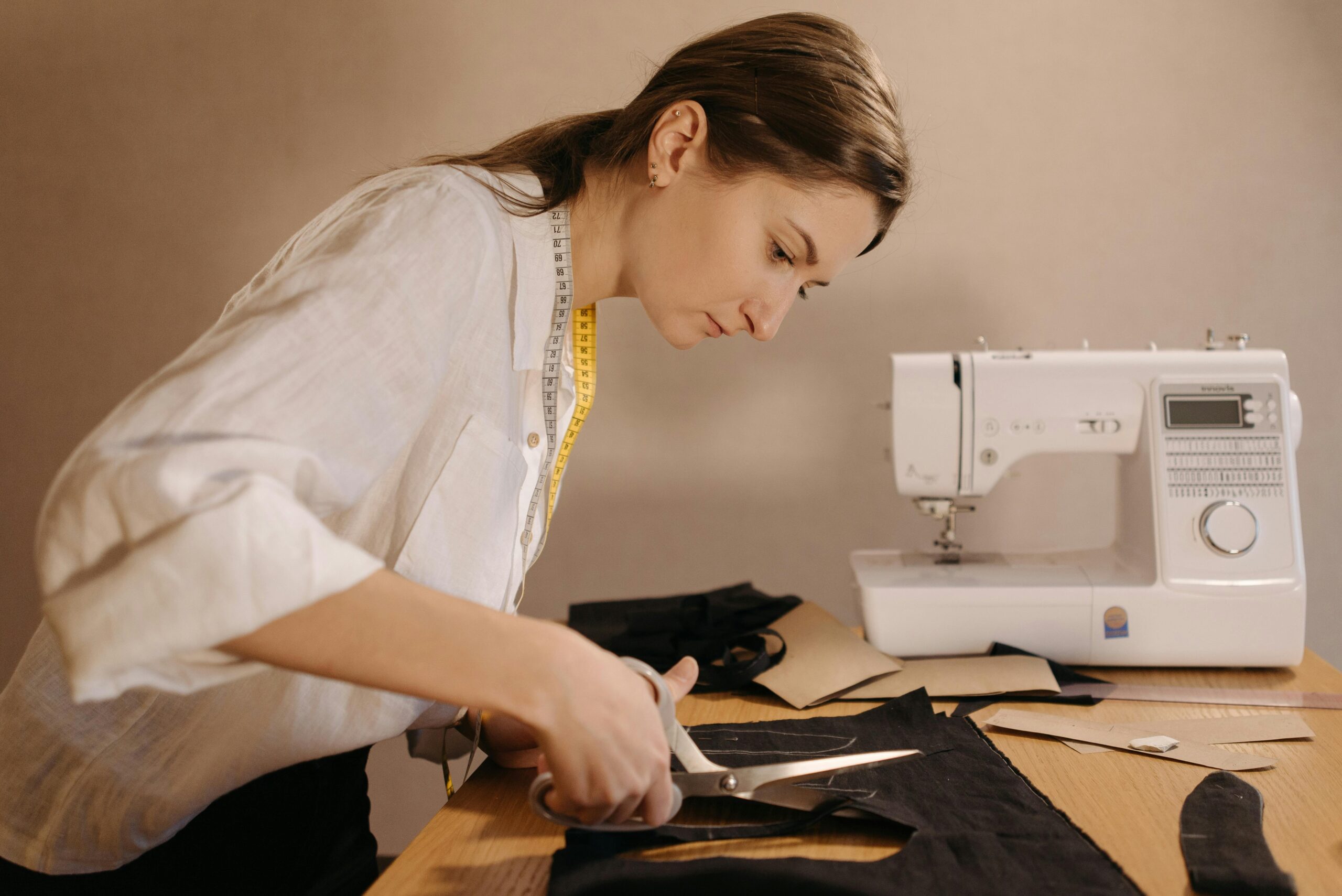 A skilled tailor cutting fabric beside a sewing machine, focused on creating fashion.