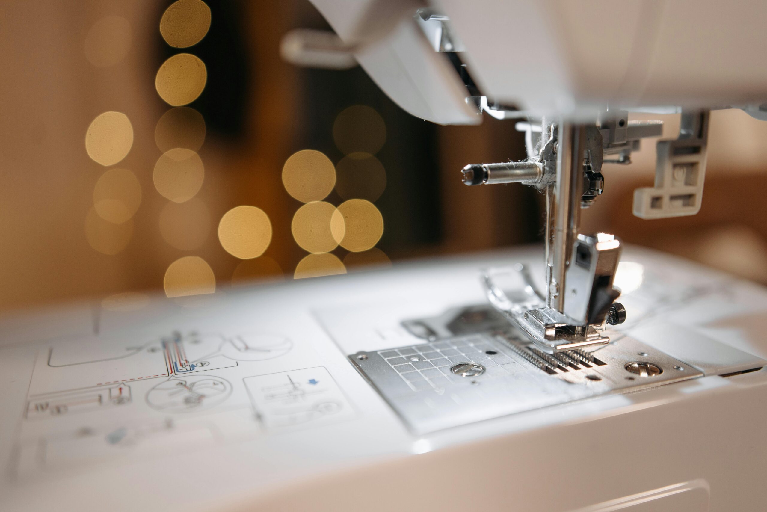 Detailed view of a sewing machine needle and parts with bokeh background, showcasing precision engineering.