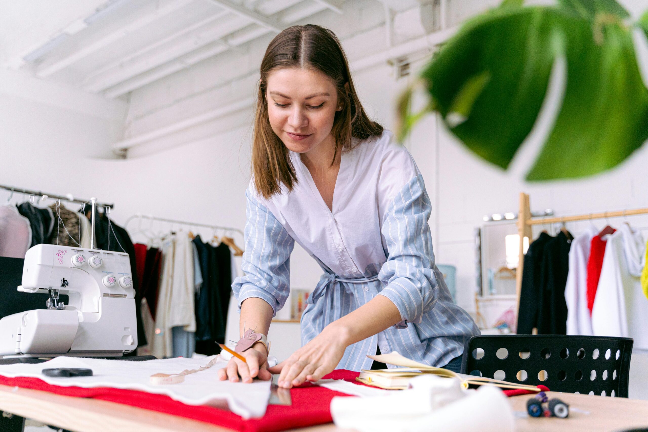 A woman focused on cutting fabric with a sewing machine in a modern tailoring shop.