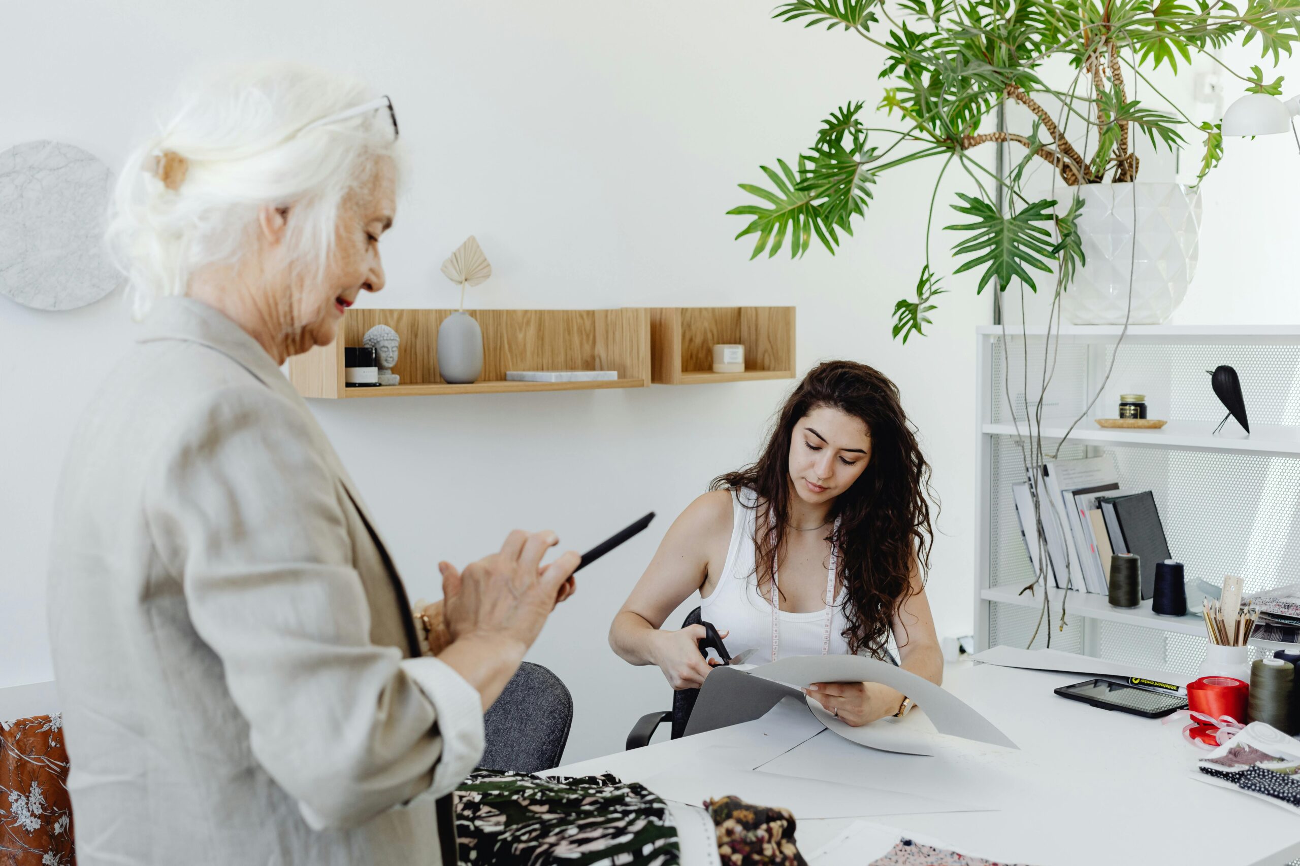 Two women collaborating in a modern design studio with fabrics and office decor.